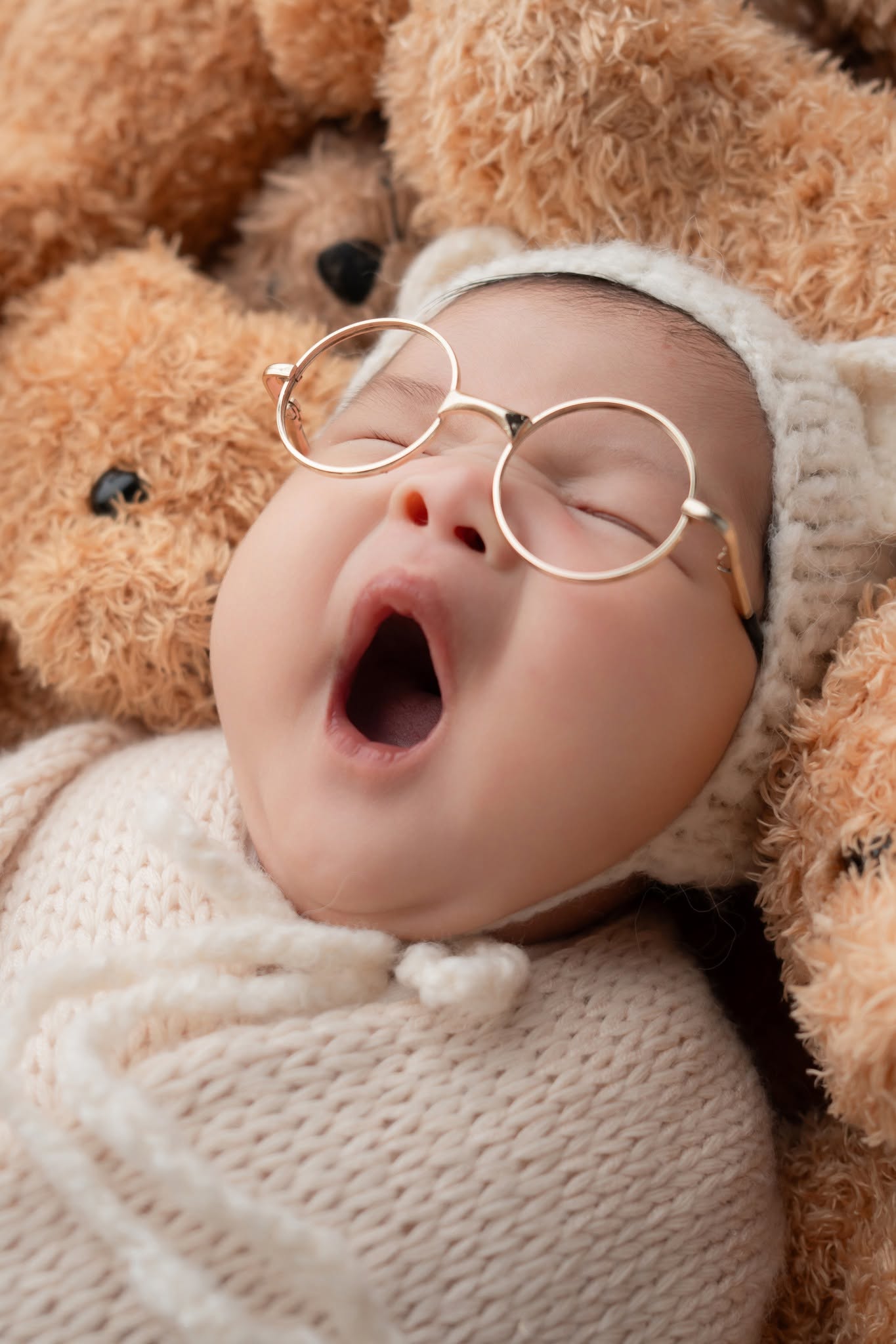 Chụp ảnh sơ sinh bé ngáp đáng yêu đeo kính tròn bên gấu bông — gói Newborn tại Kẹo Mút Studio Hà Nội